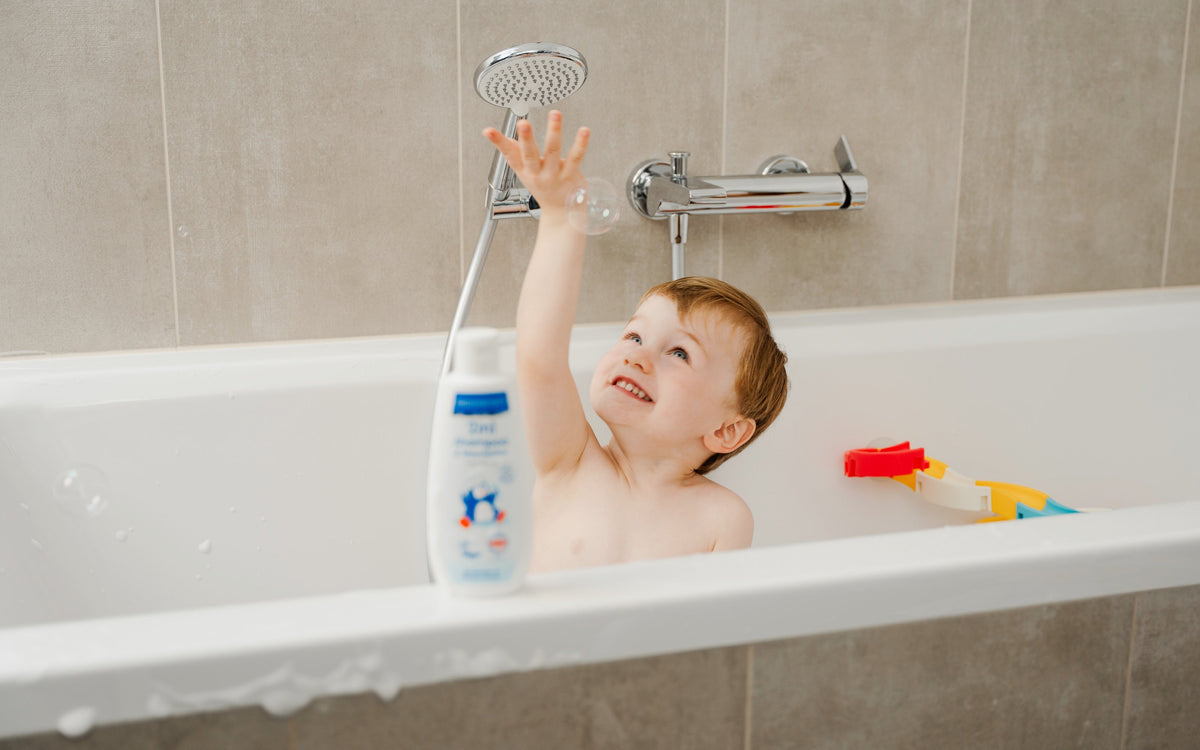 Kind in der Badewanne mit der Shampooflasche.