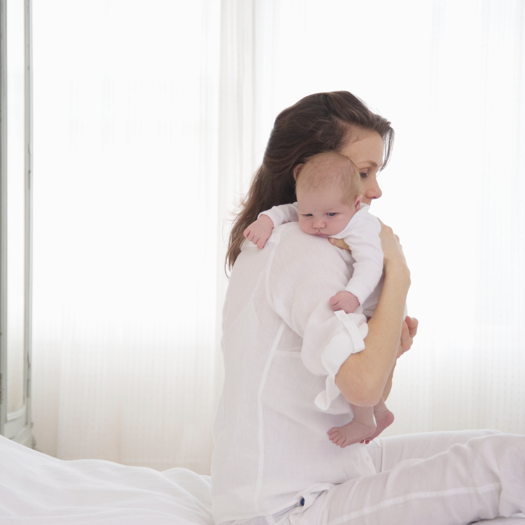 mother holding her baby on the bed