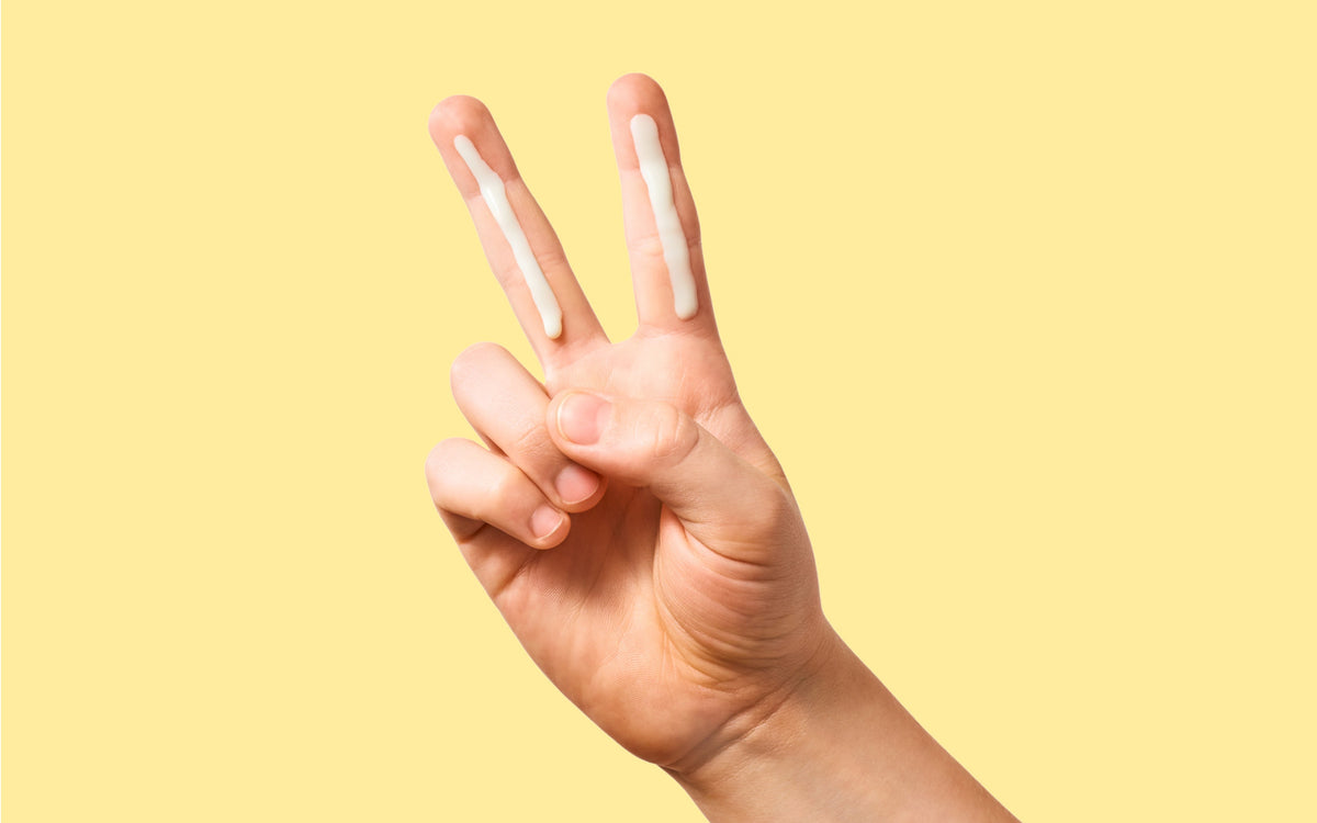 Zwei Finger mit Sonnencreme, als Peace-Zeichen.