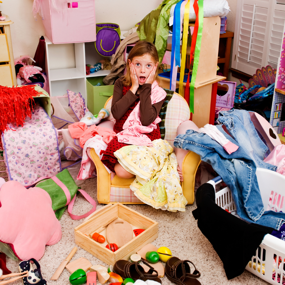 Ein junges Mädchen sitzt inmitten des Chaos in ihrem Schlafzimmer