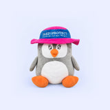 Kuscheltier Pauline, grauer Pinguin mit pinkem Hut und PAEDIPROTECT Schriftzug.