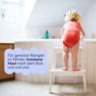 Kleinkind auf einem Hocker am Waschbecken: für gereizte Wangen im Winter und trockene Haut nach dem Bad.