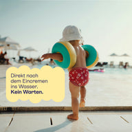 Kind mit Schwimmflügeln am Beckenrand: direkt nach dem Eincremen ins Wasser, kein Warten.