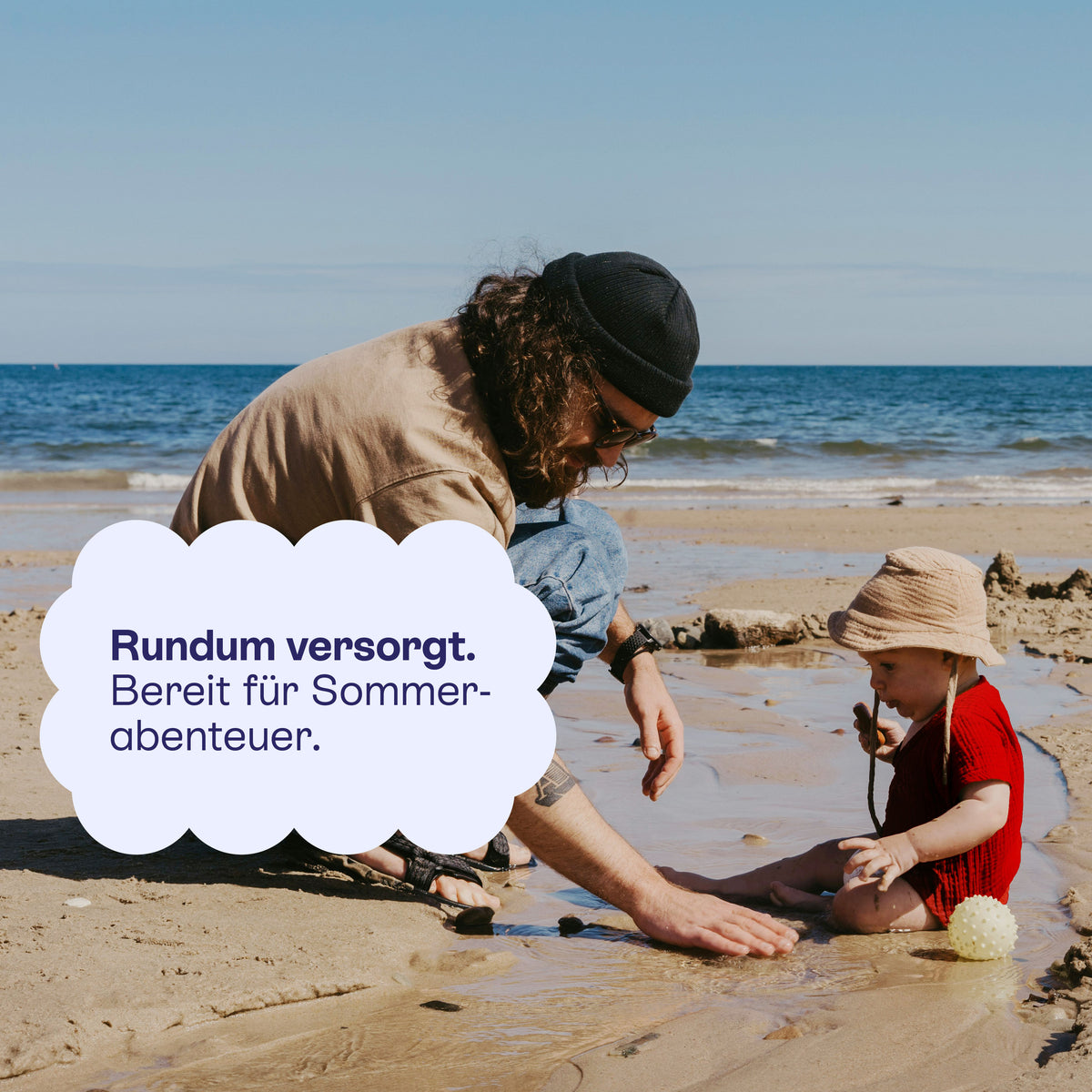 Erwachsener und Kind spielen im Sand: rundum versorgt für Sommerabenteuer.