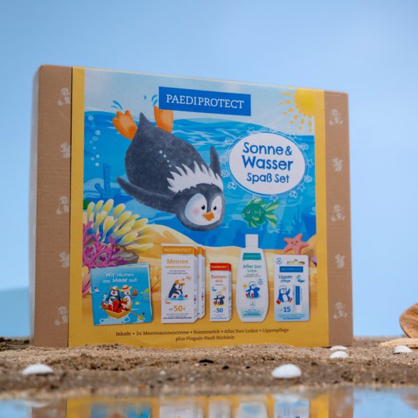 Sonne & Wasser Spaß Set auf Sand, der sich im Wasser spiegelt, mit hellblauem Hintergrund