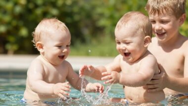 Baby und Kind spielen im Sommerwasser mit Sonnenlicht.