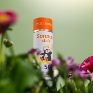 Der PAEDIPROTECT Sonnenstick lugt hinter Blumen hervor