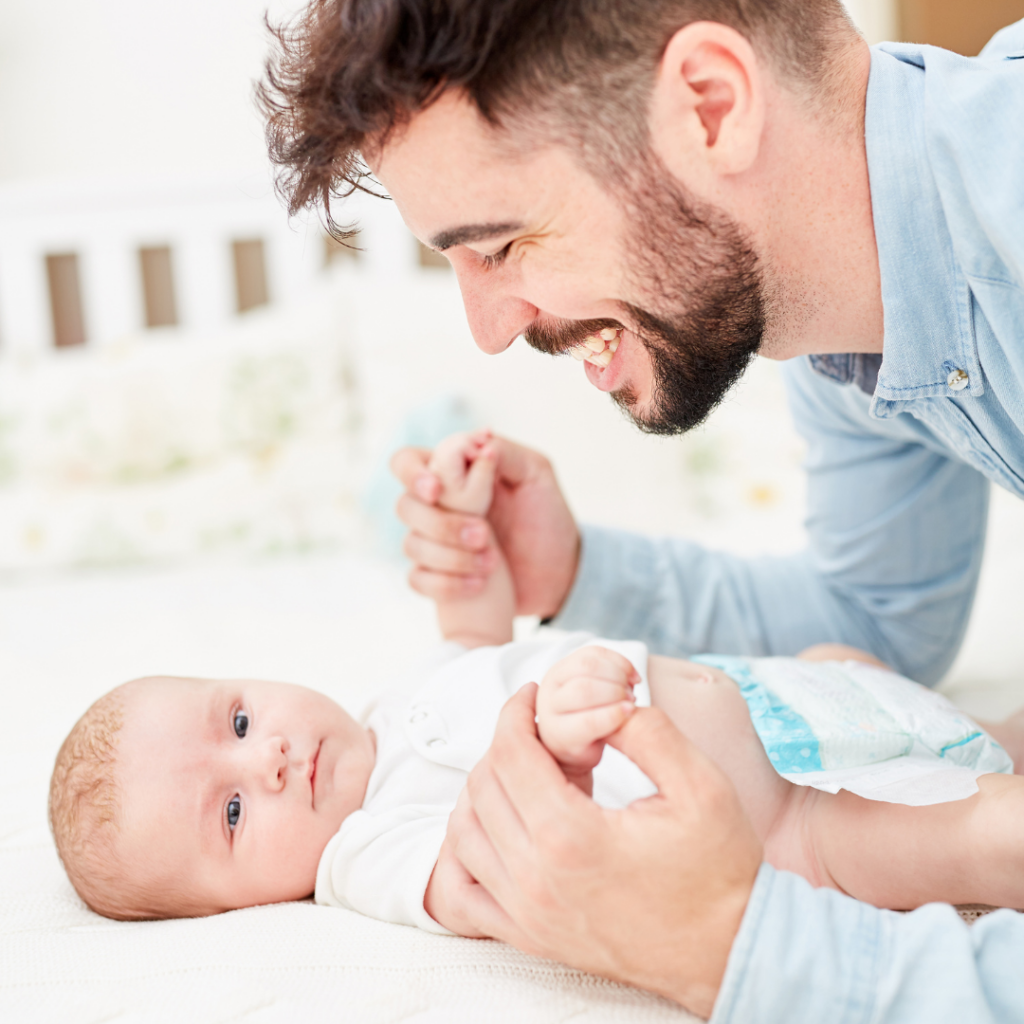 Baby wickeln: Papa spielt mit seinem Baby auf den Wickeltisch