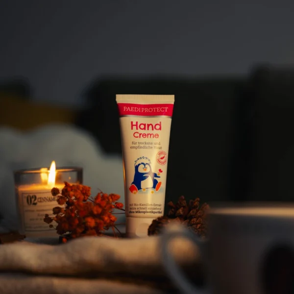 a hand cream tube and candle on a table