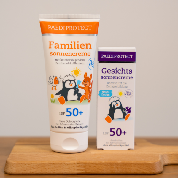 Auf einem kleinen Holzbrett ist die Familiensonnencreme und die Gesichtssonnencreme aufgestellt